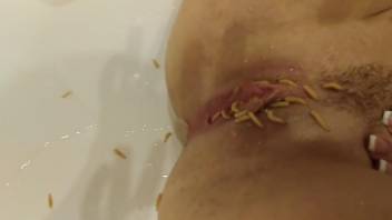Nude slut masturbates with worms deep in both holes